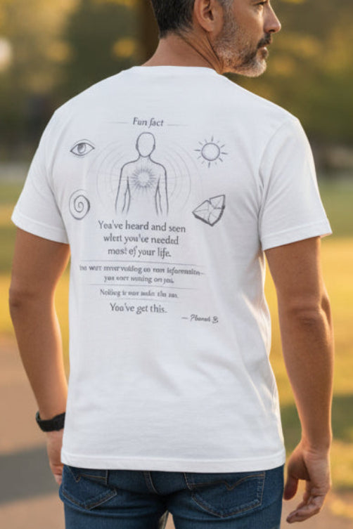 Man wearing a white t-shirt with graphics and text, standing on a path in a park.