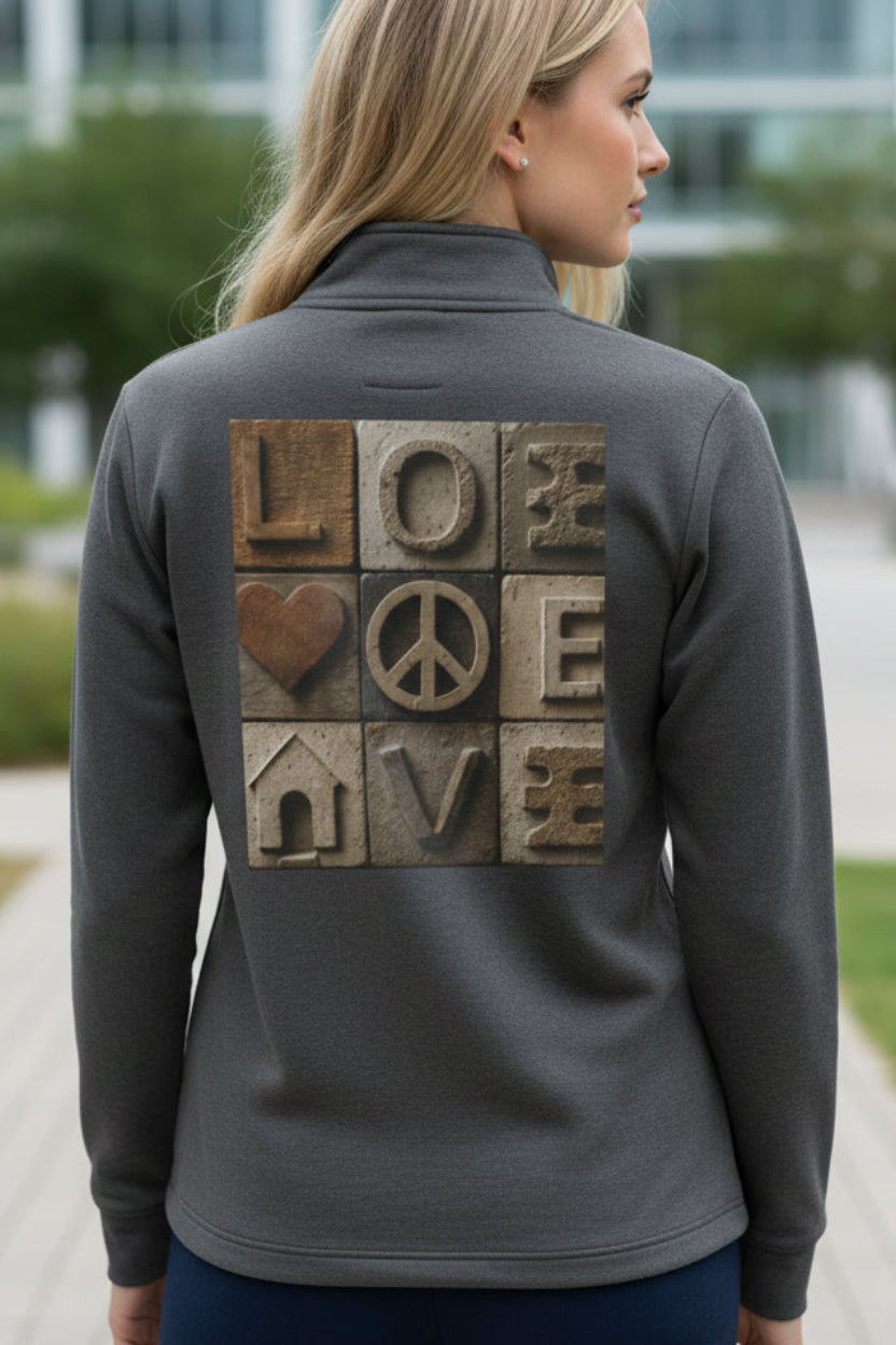 Woman wearing a gray jacket with a back design of 'LOVE' and peace symbol, outdoors.