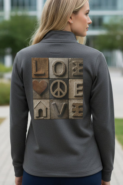 Woman wearing a gray jacket with a back design of 'LOVE' and peace symbol, outdoors.